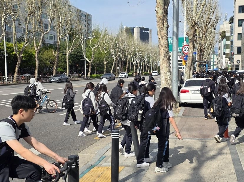 자전거도로에 불법 주차 차량으로 인해 도로를 통해 이동하는 학생들