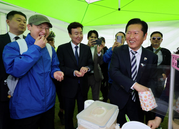 더불어민주당 정청래 대표가 18일 울산시 남구 태화강 둔치에서 열린 ‘울산 자전거 대축전’을 찾아 자전거 페달을 굴려 팝콘을 튀기는 체험을 한 후 김상욱 울산시장 후보, ‘영입인재 1호’ 전태진 변호사와 팝콘을 나눠 먹고 있다. 2026.4.18  연합뉴스