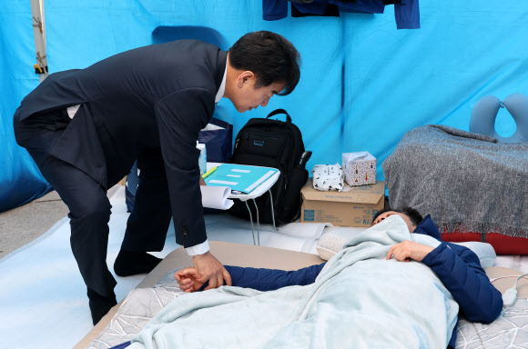 더불어민주당 문진석 의원이 22일 국회 본청 앞에서 단식 12일 차를 맞은 안호영 의원의 천막 농성장을 찾아 대화하고 있다. 2026.4.22 연합뉴스