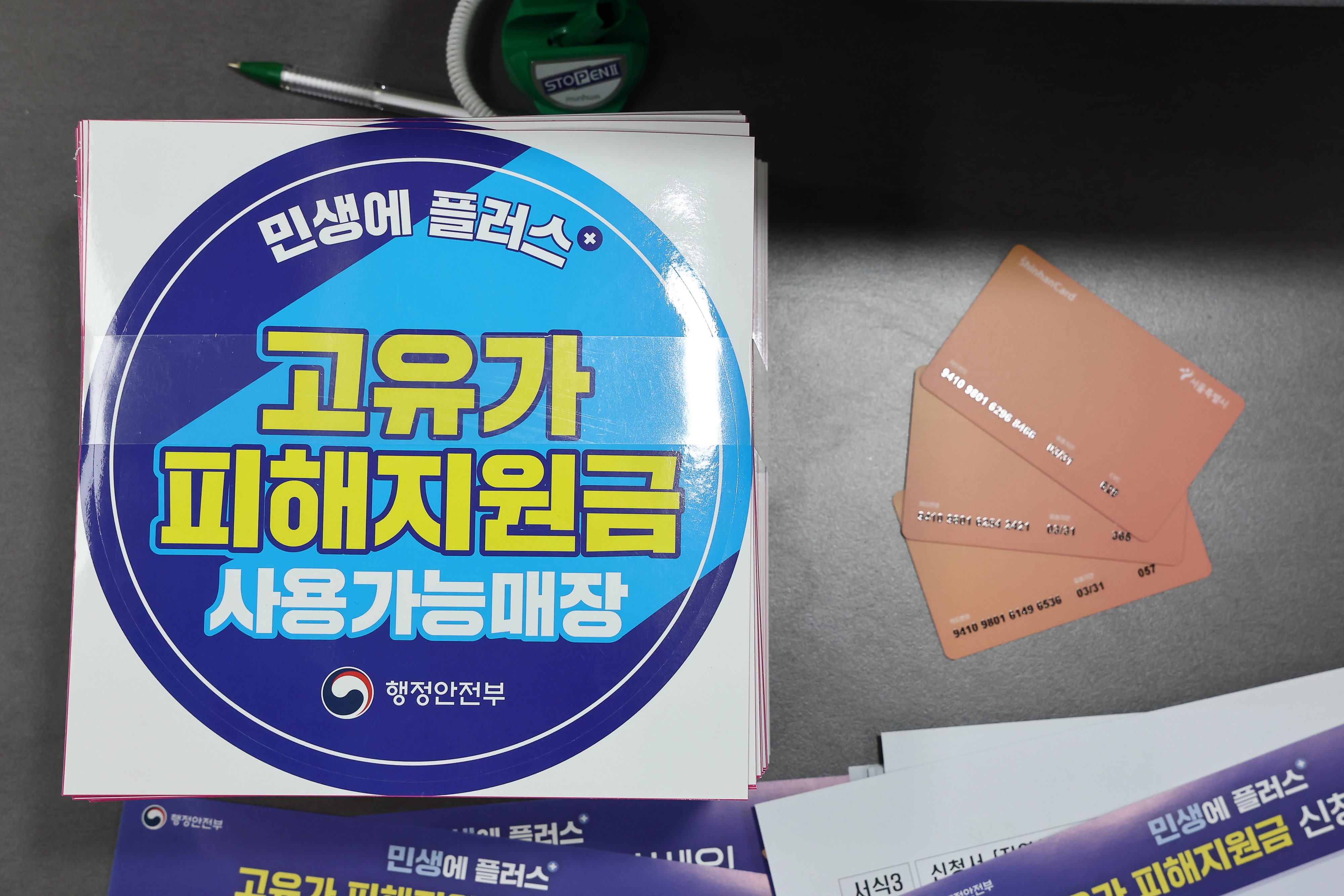27일부터 고유가 피해지원금 지급  24일 서울 숭인2동주민센터에 마련된 고유가 피해지원금 신청 창구에 관련 부착물과 사용 카드가 놓여 있다. 고유가 피해지원금은 이달 27일부터 5월 8일까지 기초생활수급자·차상위가구·한부모가족을 대상으로 우선 지급한다. 연합뉴스