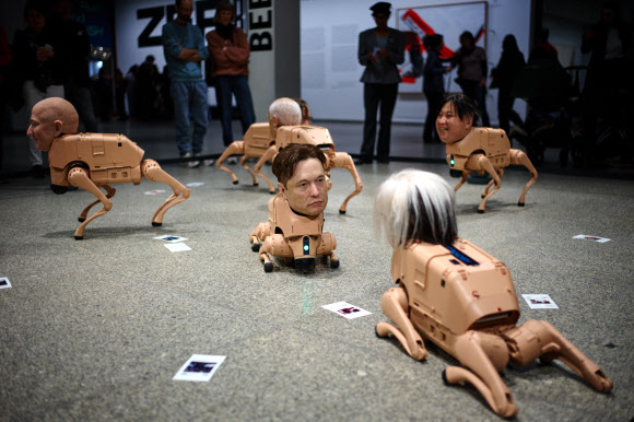 28일(현지시간) 독일 베를린의 신국립미술관에서 열린 디지털 아티스트 비플(본명 마이크 윙켈만)의 ‘레귤러 애니멀스’ 설치 미술 전시에 제프 베이조스, 일론 머스크, 앤디 워홀, 김정은의 얼굴을 한 로봇들이 전시돼 있다. AP 연합뉴스