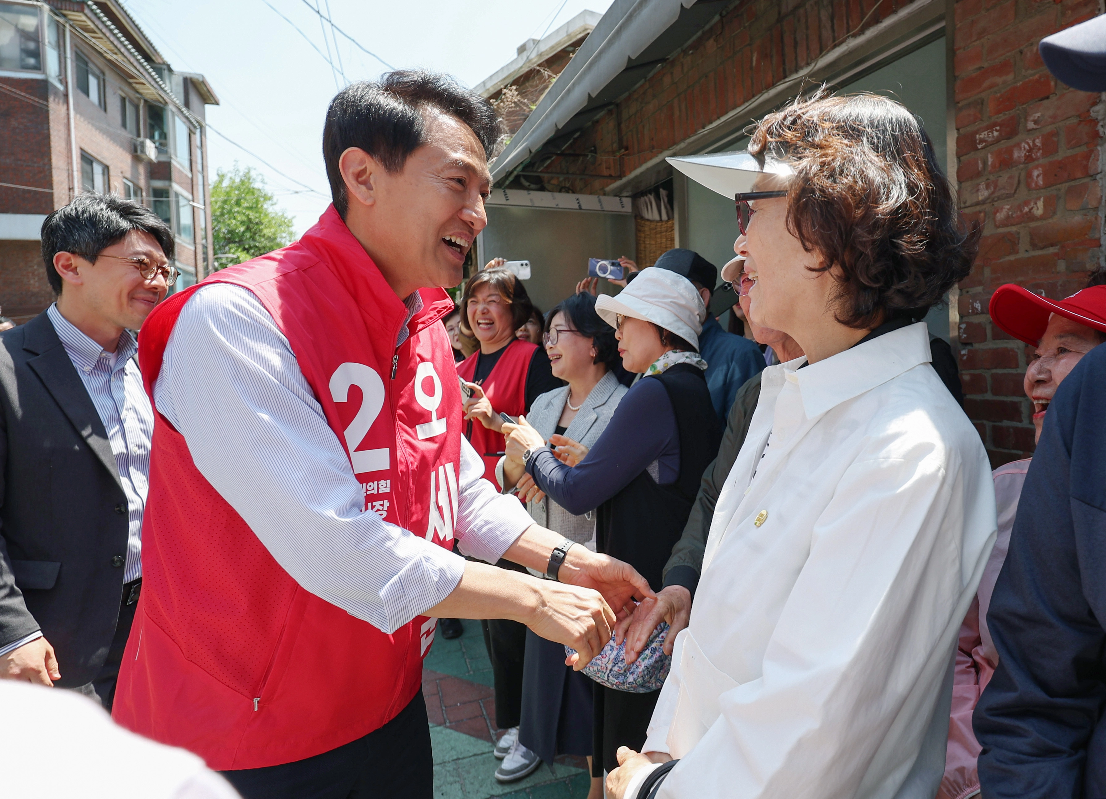 오세훈 국민의힘 서울시장 후보가 13일 서울 강동구 일대 주택가에서 부동산지옥 시민대책회의 기자회견을 하기 위해 참석하던 중 시민들과 인사를 나누고 있다. 뉴시스