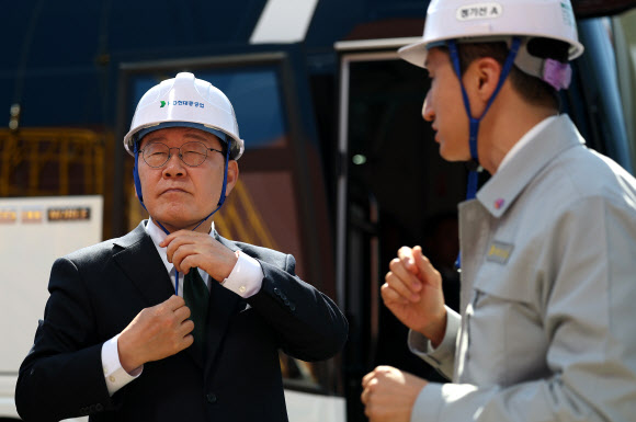 이재명 대통령이 13일 HD현대중공업 울산 조선소에서 LNG 화물선 시찰에 앞서 안전모를 착용하고 있다. 오른쪽은 정기선 HD현대 회장. 2026.5.13 연합뉴스