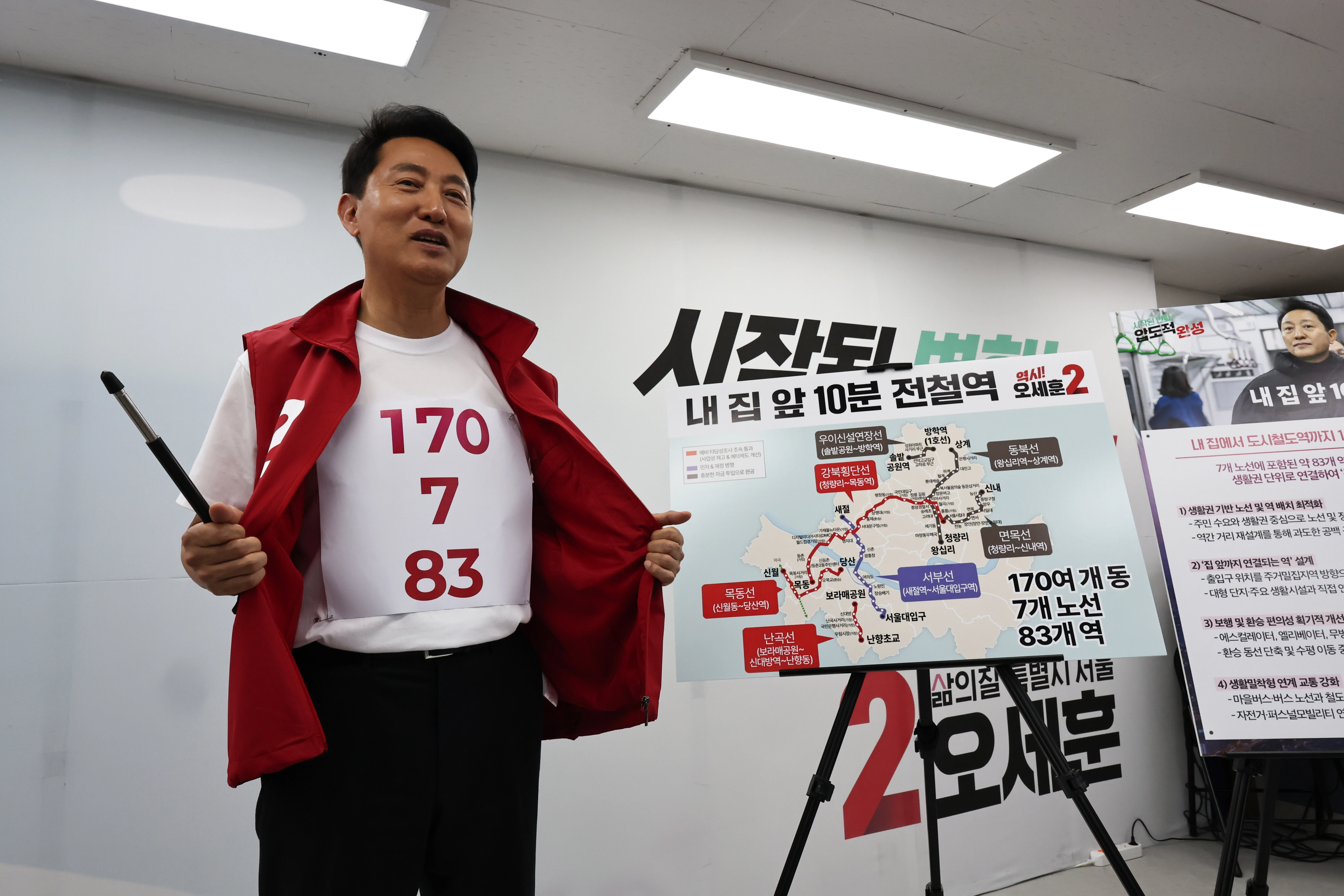 국민의힘 오세훈 서울시장 후보가 26일 서울 종로구 대왕빌딩 선거캠프에서 도시철도 공약을 발표하며 전철역 노선 계획 숫자가 적힌 티셔츠를 보여주고 있다. 연합뉴스
