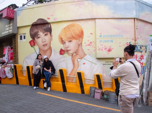 그룹 방탄소년단(BTS) 팬인 ‘아미’들이 감천문화마을에서 BTS 멤버 지민과 정국의 얼굴을 그린 벽화를 배경으로 기념사진을 찍고 있다. 부산은 두 사람의 고향이다.
사하구 제공