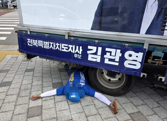 1일 오전 전북 전주시 완산구의 한 네거리에서 더불어민주당 이원택 전북특별자치도지사 후보의 선거운동원이 무소속 김관영 후보 유세차 밑으로 들어가 드러누워 있다. 2026.6.1. 연합뉴스