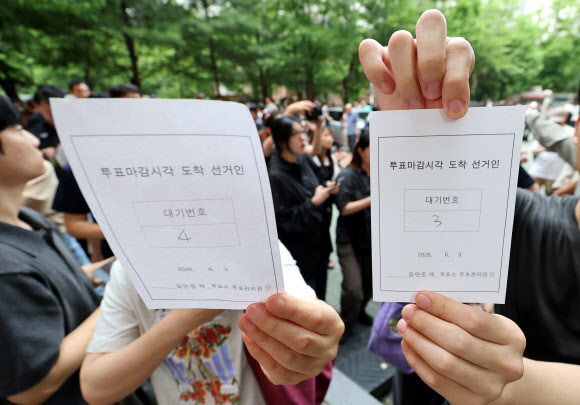 6·3 지방선거 본투표일인 3일 서울 송파구 잠실2동 6투표소에서 투표용지 부족으로 대기하던 한 유권자들이 마감시간 후 대기번호표를 들어 보이고 있다. 2026.6.3  연합뉴스