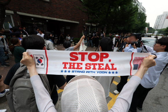 전날 9회 전국동시지방선거 및 국회의원 재·보궐선거 투표용지 부족으로 투표 시간이 오후 10시까지 연장됐던 서울 송파구 잠실7동 제2투표소 앞에서 4일 투표함 반출에 반대하는 시민들이 손팻말을 들고 구호를 외치고 있다. 2026.6.4 연합뉴스