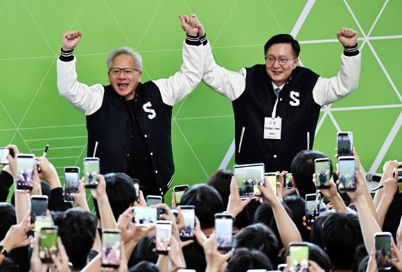 젠슨 황 엔비디아 최고경영자(CEO)가 8일 서울대학교 해동첨단공학관에서 열린 ‘빌드어클로(Build-a-Claw)’ 행사장에서 유홍림 서울대 총장(오른쪽)으로부터 학교 점퍼를 선물받은 뒤 환호하고 있다. 2026.6.8  공동취재