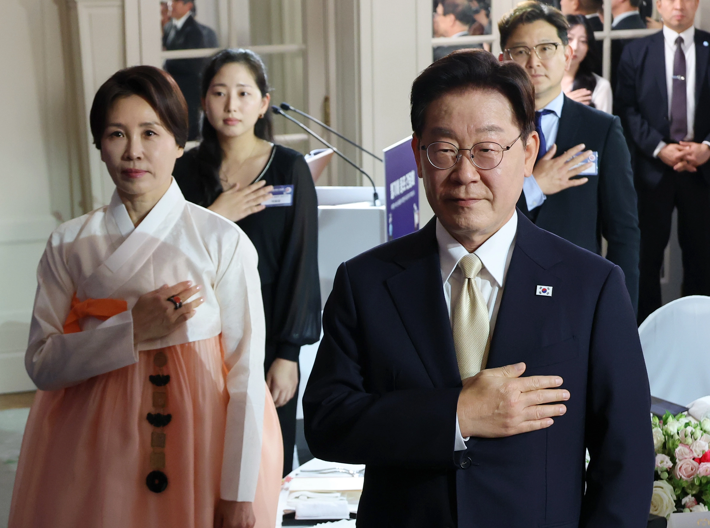 이재명 대통령, 벨기에 동포 만찬간담회 참석  이재명 대통령과 김혜경 여사가 9일(현지시간) 벨기에 브뤼셀 한 호텔에서 열린 동포 만찬간담회에서 국기에 경례하고 있다. 
브뤼셀 연합뉴스