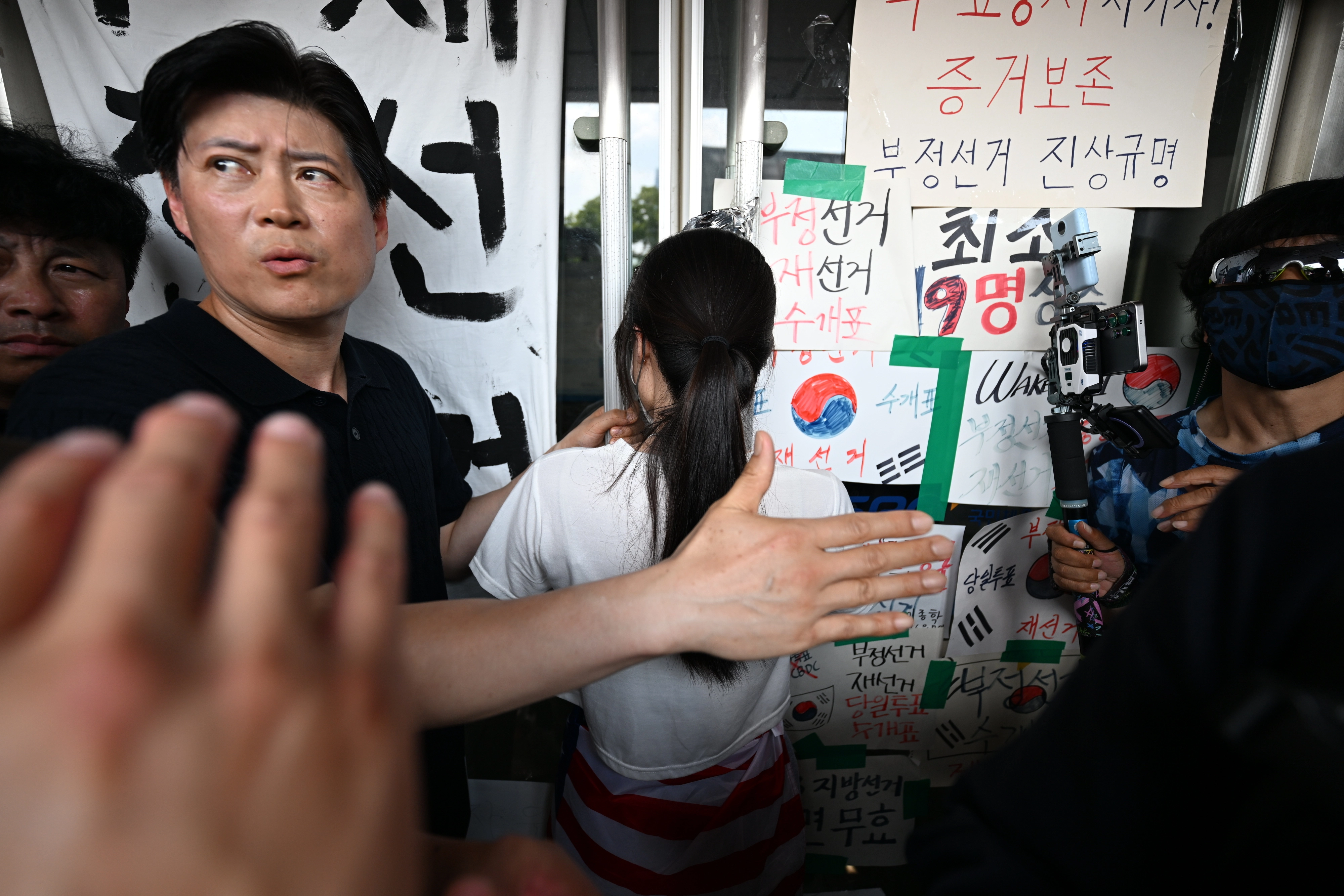 6·3지방선거 투표용지 부족 사태로 촉발된 잠실 개표소 봉쇄 시위가 12일째 이어진 16일 시민들이 서울 송파구 올림픽공원 핸드볼경기장 2-1 출구 앞 문을 지키고 있다. 홍윤기 기자