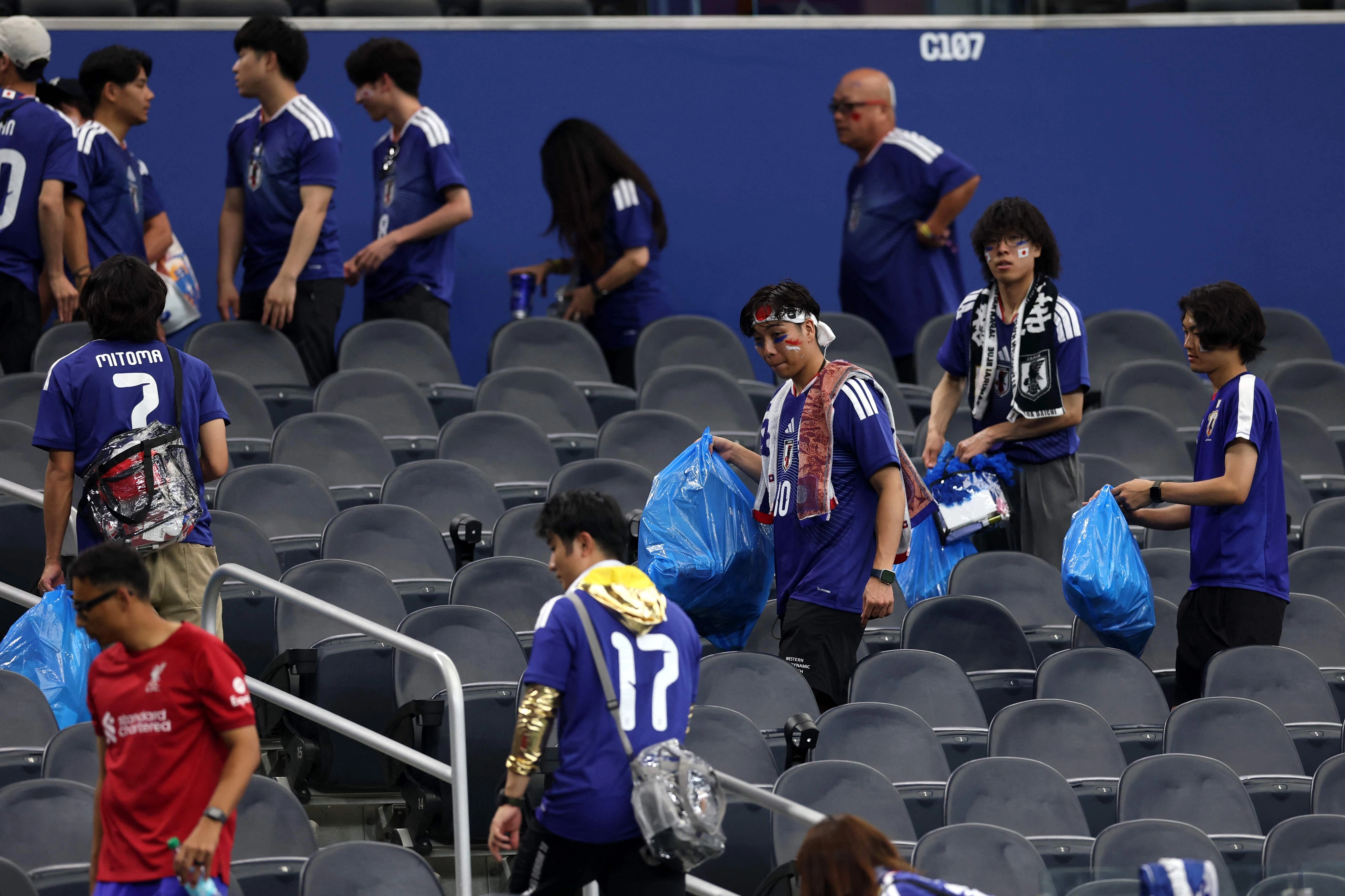 일본 축구팬들이 15일 북중미 월드컵 네덜란드전이 끝난 뒤 관중석 쓰레기를 치우고 있다. AFP연합뉴스