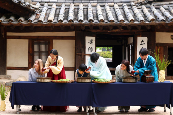 단오(음력 5월 5일)를 앞둔 17일 서울 종로구 국립민속박물관 오천댁 앞에서 열린 단오 세시행사에서 외국인 관광객이 창포물 머리감기 체험을 하고 있다. 2026.6.17  연합뉴스