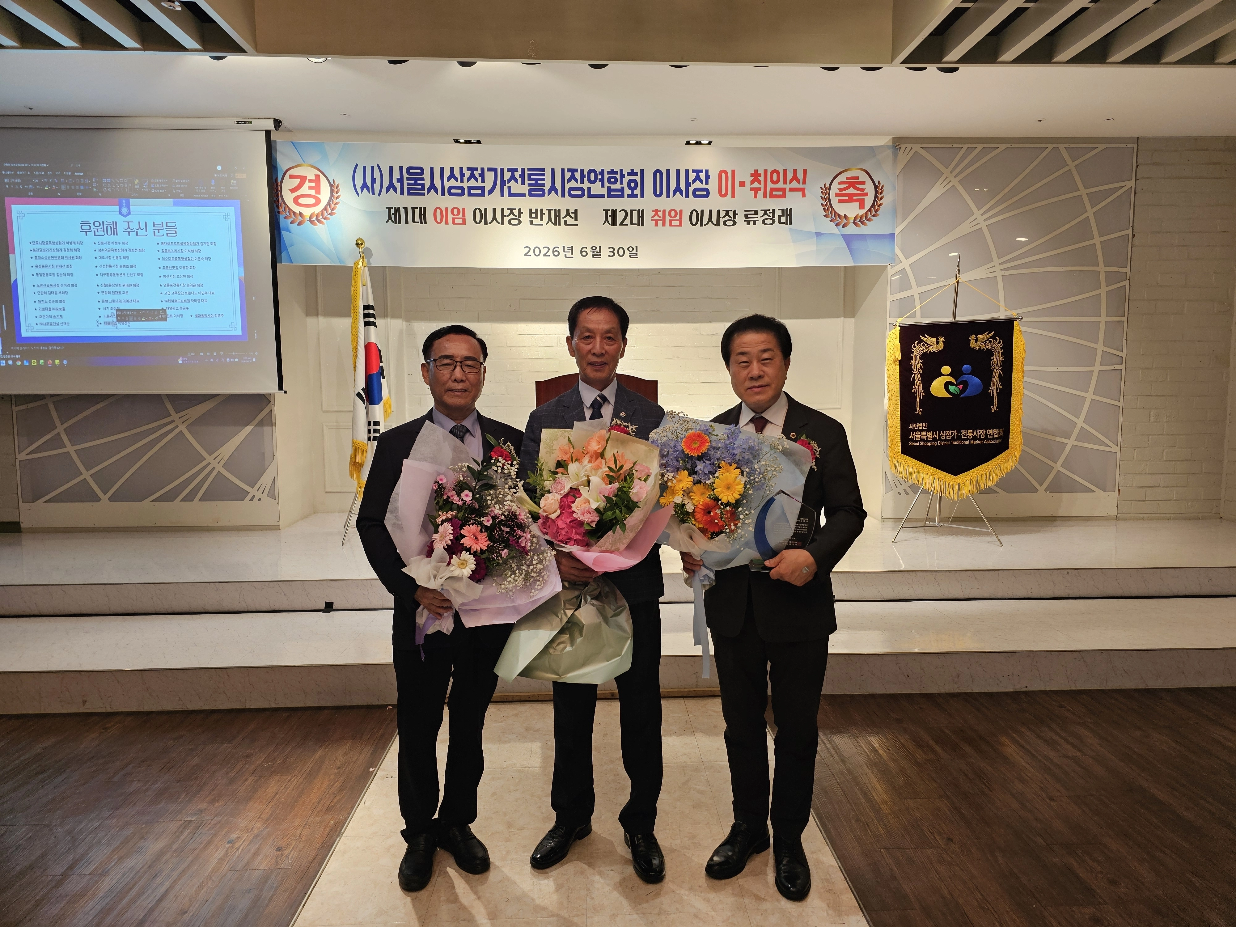 지난 6월 30일 파티앤프렌즈 피에스타홀에서 개최된 사)서울시상점가·전통시장 연합회(이하 ‘연합회’) 제1·2대 이사장 이·취임식에 참석한 김용호 서울시의원(오른쪽 첫 번째)이 감사패를 수상해 반재선 이사장(왼쪽 첫 번째), 류정래(중앙) 이사장과 기념촬영을 하고 있다. 서울시의회 제공