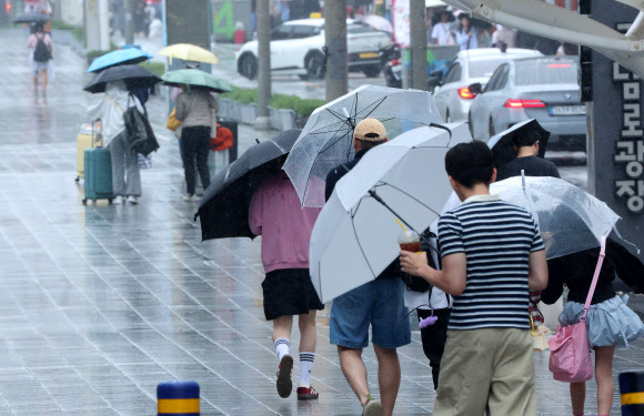 장마가 시작된 1일 부산 해운대구 구남로에서 우산을 쓴 관광객들이 발걸음을 옮기고 있다. 2026.7.1 연합뉴스