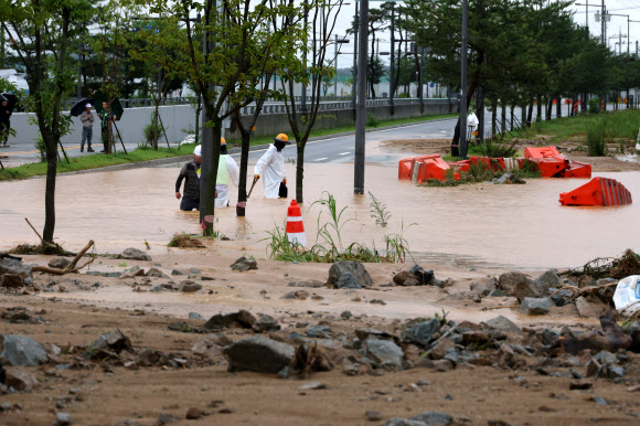 폭우가 내린 9일 세종시 한별동 BRT 교차로 부근 도로가 공사장에서 흘러내린 토사에 덮여 침수되자 작업자들이 복구작업을 벌이고 있다. 2026.7.9 연합뉴스