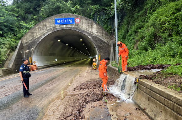 9일 오전 충북 옥천군 안내면 방하목리 문티터널 인근에서 소방대원들이 폭우로 쓸려 내려온 토사에 막힌 배수구를 뚫고 있다. 2026.7.9 옥천소방서 제공