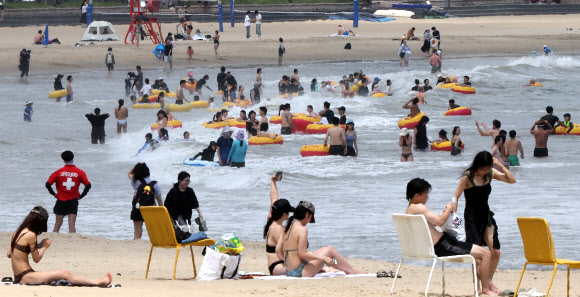 13일 전국에 폭염이 이어진 가운데 부산 수영구 광안리해수욕장을 찾은 시민과 관광객들이 바닷물에 몸을 담그고 튜브를 탄 채 물놀이를 즐기며 더위를 식히고 있다. 2026.7.13  연합뉴스