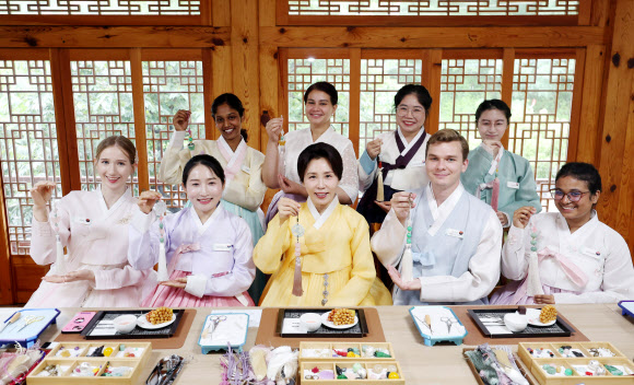 김혜경 여사가 20일 서울 종로구 부암동 무계원 사랑채에서 외국인 청년들과 직접 만든 한국 전통공예 노리개를 들고 기념촬영을 하고 있다. 2026.7.20  청와대통신사진기자단