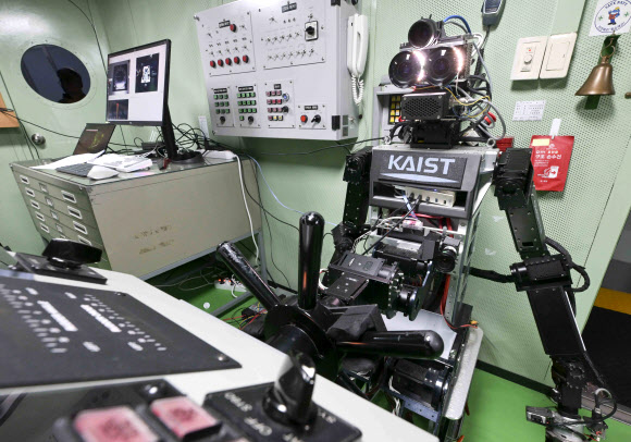지난 23일 해군교육사령부 조함훈련장에서 해군 최초로 진행된 로봇 승조원 전투실험에서 휴머노이드 로봇 ‘파이봇(PIBOT)’이 이지스구축함 서애류성룡함(DDG) 소속 함교 당직사관의 조함명령에 따라 타수 업무를 수행하고 있다. 2026.7.24  해군 제공