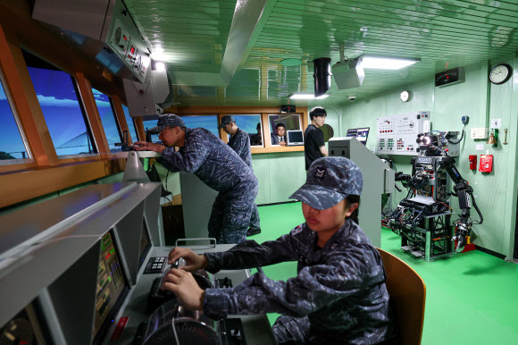 지난 23일 경남 창원시 진해구 해군교육사령부 조함훈련장 시뮬레이터에서 진행된 ‘해상 당직업무 수행 로봇 전투실험’에서 한국과학기술원이 개발한 인간형 로봇 ‘파이봇’이 조타수 임무를 수행하고 있다. 2026.7.24  사진공동취재단
