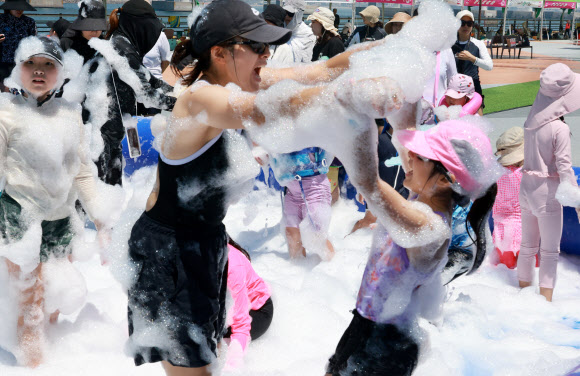 27일 부산 남구 용호별빛공원에서 열리고 있는 ‘제4회 유엔남구 물놀이축제’에서 한 가족이 거품을 묻히며 더위를 식히고 있다. 2026.7.27 연합뉴스