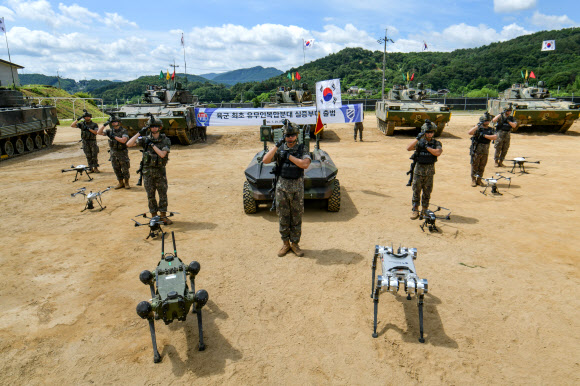 29일 강원 홍천 11기동사단 철마부대에서 열린 유무인복합분대 실증부대 출범식에서 장병들이 다족형로봇, 드론 등 무인체계와 함께 도열해 경례하고 있다. 2026.7.29  육군 제공
