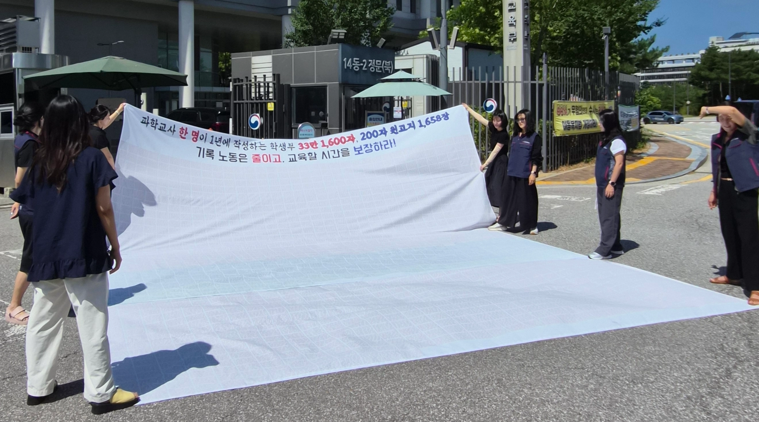 교사노동조합연맹이 31일 정부세종청사 교육부 앞에서 기자회견을 열고 학교생활기록부(학생부) 제도 전면 개편을 촉구하며 현수막 퍼포먼스를 하고 있다. 교사노조 제공
