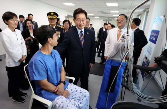 이재명 대통령이 11일 충북 음성 국립소방병원에서 재활 치료 중인 환자를 격려하고 있다. 오른쪽은 곽영호 병원장. 2026.8.11. 청와대통신사진기자단