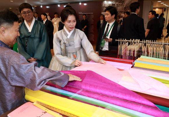 김혜경 여사가 14일 서울 중구 동대문디자인플라자에서 열린 한복박람회 ‘2026 한복상점’에서 원단을 보고 있다. 2026.8.14  연합뉴스