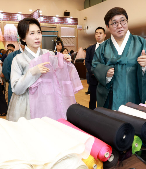 김혜경 여사가 14일 서울 중구 동대문디자인플라자에서 열린 한복박람회 ‘2026 한복상점’에서 실크셔츠를 보고 있다. 오른쪽은 최휘영 문화체육관광부 장관. 2026.8.14 연 합뉴스