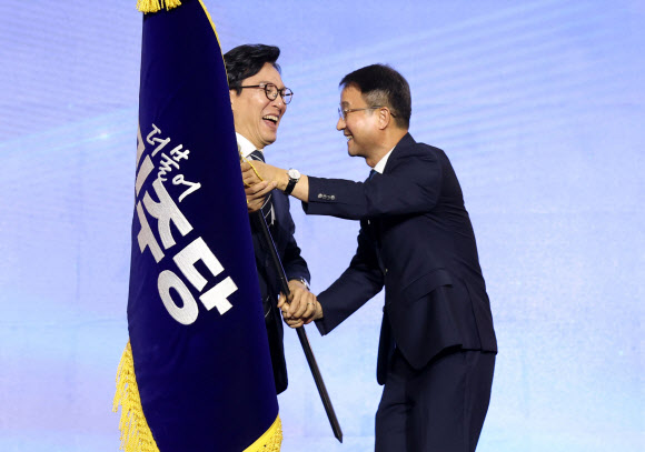 더불어민주당 김민석 신임 당 대표가 17일 대전 컨벤션센터에서 열린 제3회 더불어민주당 정기 전국당원대회에서 당 대표로 선출된 뒤 당기를 전달받고 있다. 2026.8.17  연합뉴스
