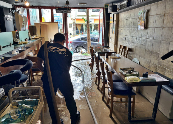 18일 오전 극한호우 피해를 본 경남 거제시 옥포동 한 가게에서 소방관이 배수 작업을 하고 있다. 2026.8.18. 경남소방본부 제공