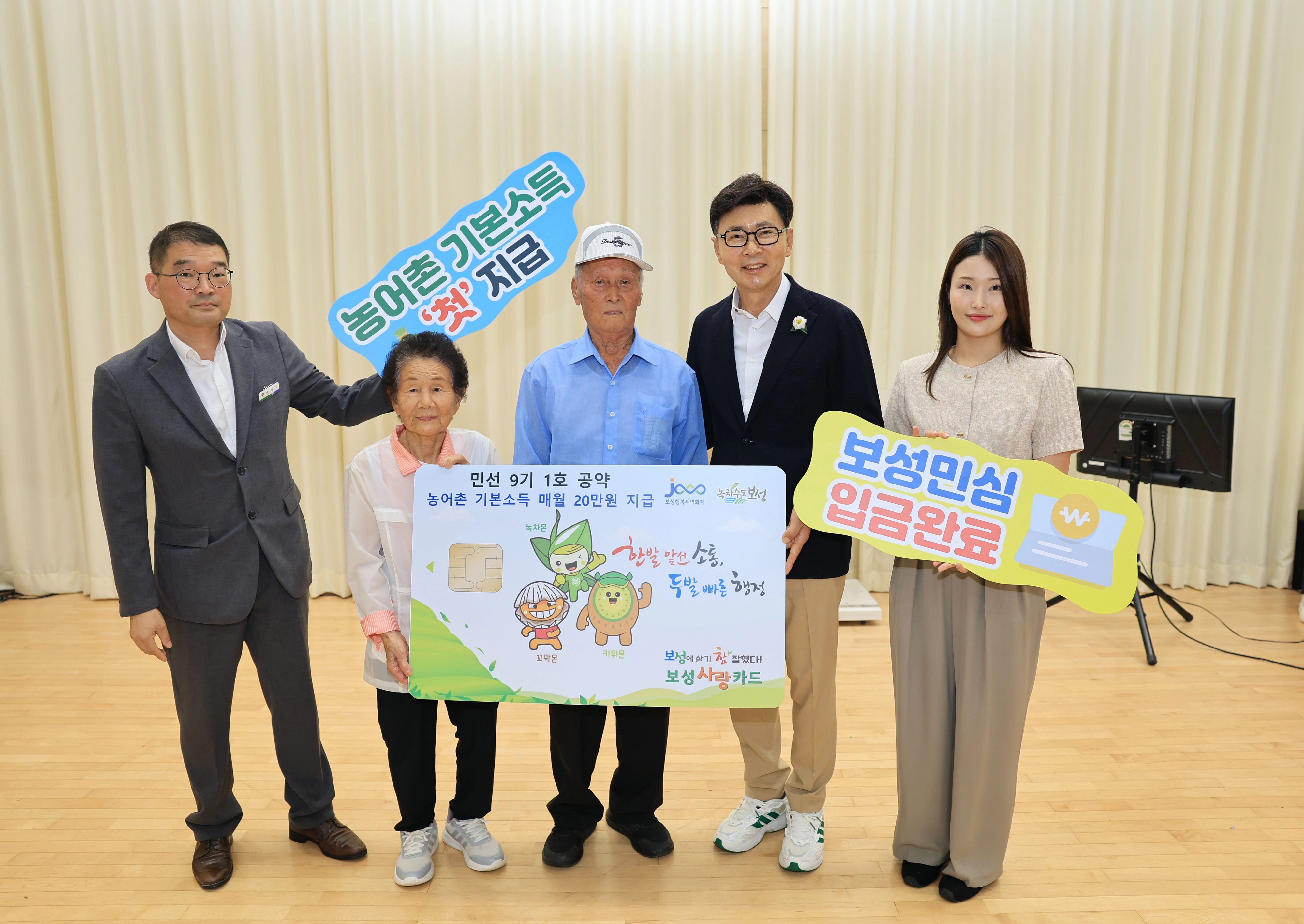 김철우 보성군수가 장수 노인 부부에게 주민 대표로 보성사랑상품권 카드 모형을 전달했다.