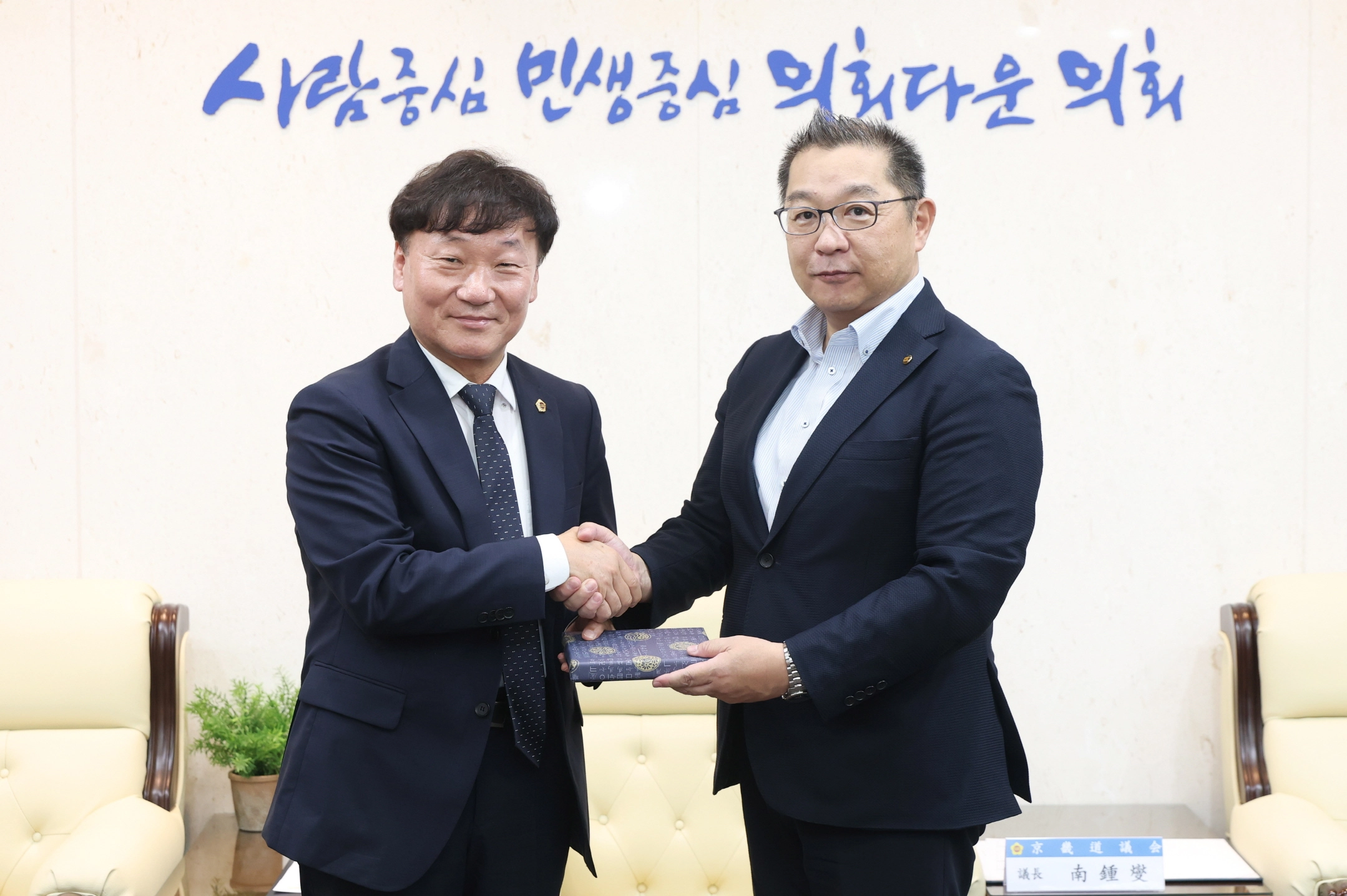 ▲남종섭 의장(왼쪽)이 2일 도의회 접견실에서 아베 요시히로 일본노총 가나가와연합 사무국장과 악수를 나누며 기념품을 교환하고 있다. (사진=경기도의회)