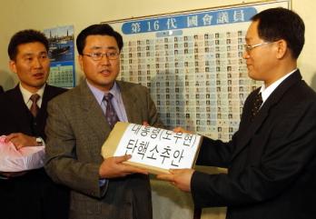 민주당 당직자가 9일 오후 한나라당·민주당 의원 159명이 서명한 ‘노무현 대통령 탄핵소추안’을 노재석(오른쪽) 국회 의사국장에게 제출하고 있다.  남상인기자 sanginn@