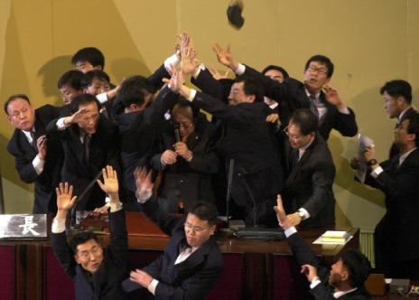 이꼴을 봐야 하나… 박관용(가운데 마이크 든 이) 국회의장이 지난 12일 의장석으로 구두가 날아드는 난장판 속에서 야당 의원과 경위들의 경호를 받아가며 대통령 탄핵소추안 가결을 선포하고 있다. 서울신문 포토라이브러리