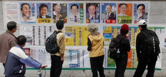 "우리동네 누가 나왔나" 17대 총선 선거벽보(선전벽보)를 지나는 주민들이 유심히 살펴보고 있다. 서울신문 포토라이브러리