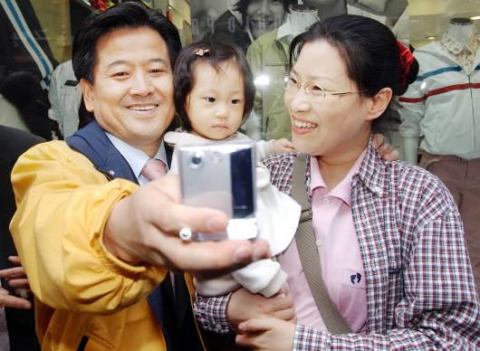 춘천서 열린우리당 정동영(왼쪽) 의장이 9일 강원도 춘천 명동에서 지원유세를 하던 도중 아이를 안은 한 여성 유권자와 카메라폰으로 기념사진을 찍고 있다. 남상인기자 sanginn@