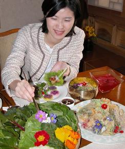 한식당 봉래정의 꽃 요리들.하미선 메이필드호텔 판촉과 대리가 꽃쌈으로 돼지고기 수육을 싸고 있다.