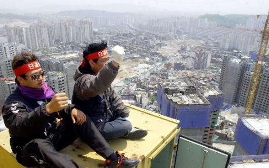 '고공농성' 기사들 6일 서울 성북구 길음동의 아파트 건설현장에 설치된 타워크레인 위에서 이틀째 고공 농성을 벌이고 있는 크레인 기사들이 임금인상 등의 구호를 외치고 있다. 정연호기자 tpgod@