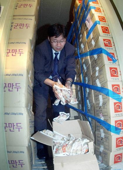 불량재료가 들어간 만두를 생산한 것으로 10일 발표된 경기도 성남시 상대원동 고향냉동식품에서 식품의약품안전청 단속반원이 포장된 군만두를 풀어보고 있다.  성남 정연호기자 tpgod@seoul.co.kr