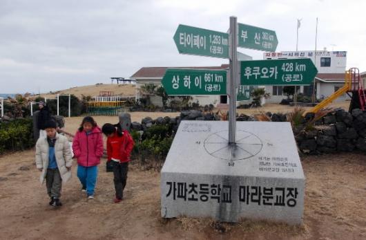 마라분교 앞에 세워진 국내 유일의 국제 이정표가 눈길을 끈다. 마라분교생 3명이 걸어나오며 미래의 꿈을 꾸듯 그 옆을 지나가고 있다. 도준석기자 pado@seoul.co.kr