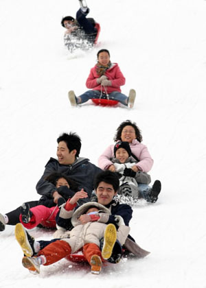 과천 서울랜드에서 겨울의 별미인 눈썰매의 재미에 푹 빠져있는 가족들.