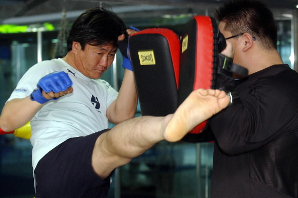 역경을 체력단련으로 극복한 한양증권 신종우(왼쪽) 이사가 15일 서울 강남의 이종격투기 체육관에서 스파링 파트너에게 ‘하이킥’을 하고 있다. 도준석기자 pado@seoul.co.kr