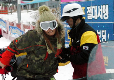 충돌사고 끝에 안전요원의 부축을 받아 스노모일에 오르고 있는 여성 스키어. 