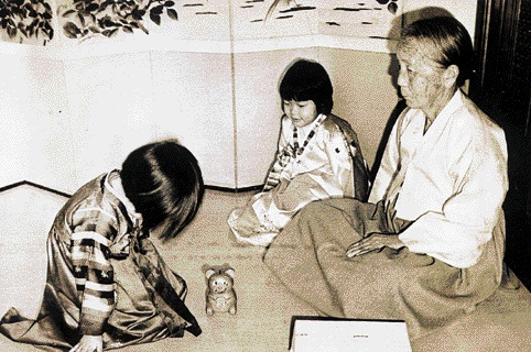 81년 설날을 맞아 색동 한복을 곱게 차려입은 손녀가 할머니에게 세배를 올리고 있다. 할머니와 손녀 사이에 놓여 있는 곰돌이 저금통은 아마도 세뱃돈을 기다리지 않을까.