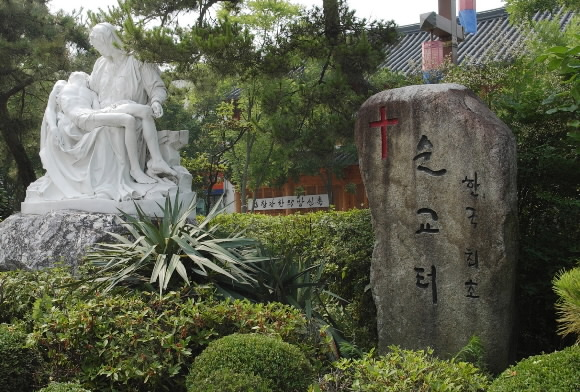 성당 정문 오른쪽 꽃담에 서 있는 선돌.‘한국 최초 순교터’라 새겨져 있다.