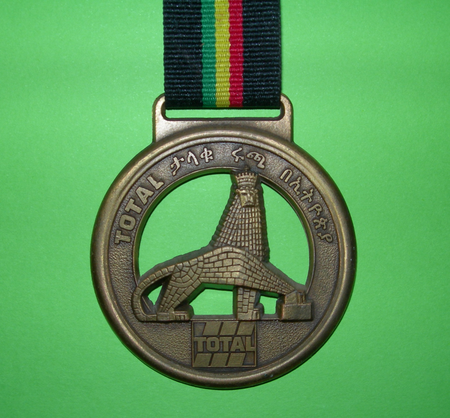 육상경기 참가자에게 주는 메달에 사용된 사자 문양. 이런 사자 문양을 에티오피아에서는 어디에서나 만날 수 있다. 이 행사는 해마다 후원업체는 다르지만 AIDS 예방 홍보를 위해 지속적으로 개최하고 있다. 사진은 2002년 프랑스의 석유회사인 TOTAL이 행사를 후원했을 때 사용했던 메달이다. 현재 미국의 Mobil이 아디스 아바바에서 철수 준비를 시작했고, 프랑스의 TOTAL이 시내의 주유소를 점령 중이다. 회사명 옆의 암하릭어는 GREAT ETHIOPIAN RUN이라는 뜻이다. 메달 뒷면에는 give value to your life 정도 의미의 암하릭어가 새겨져 있다.