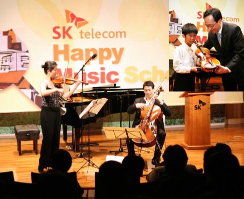 SK텔레콤이 30일 서울 을지로의 본사에서 가진 ‘해피 뮤직 스쿨’ 입학식에서 송영훈(오른쪽) 음악감독과 백주영 바이올린 파트장이 축하 연주를 하고 있다.괄호안 사진은 김신배 사장이 김진수(서울 성내초등 4년)군에게 입학증서와 함께 바이올린을 입학 선물로 주고 있는 모습. SK텔레콤 제공
